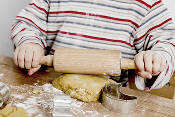 Image showing child rolling dough on wooden desk