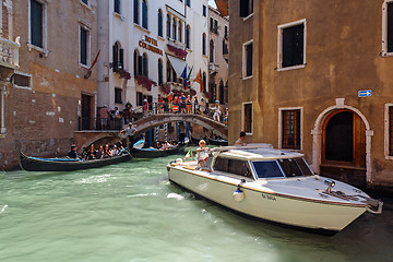 Image showing ITALY, VENICE - JULY 2012: Heavy traffic of gondolas with tourists cruising a small canal on July 16, 2012 in Venice. Gondola is a major mode of touristic transport in Venice, Italy. 