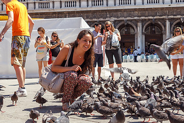 Image showing ITALY, VENICE - JULY 2012: Woman with pigeons on most famous square July 16, 2012 in Venice. More than 20 million tourists come to Venice annually.