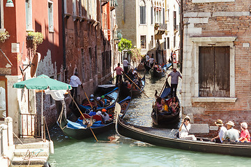 Image showing ITALY, VENICE - JULY 2012: Heavy traffic of gondolas with tourists cruising a small canal on July 16, 2012 in Venice. Gondola is a major mode of touristic transport in Venice, Italy. 