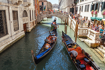 Image showing ITALY, VENICE - JULY 2012: Gondolas with tourists cruising a small Venetian canal on July 16, 2012 in Venice. Gondola is a major mode of touristic transport in Venice, Italy. 