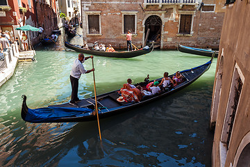 Image showing ITALY, VENICE - JULY 2012: Heavy traffic of gondolas with tourists cruising a small canal on July 16, 2012 in Venice. Gondola is a major mode of touristic transport in Venice, Italy. 