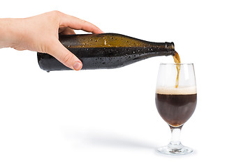 Image showing Hand holding bottle of beer and beer mug