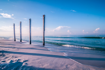 Image showing old pier pile support columns standing along the beach