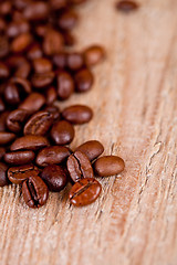 Image showing fresh coffee beans on rustic wooden board 
