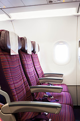 Image showing Airplane seat row in passenger cabin with window beside 