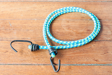 Image showing Elastic rope with metal hooks on wooden table