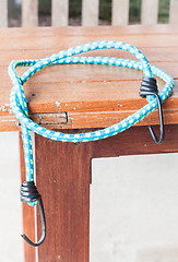 Image showing Black hooks of blue rubber band on wood table 