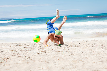 Image showing attractive young man playing volleyball on the beach