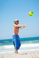 Image showing attractive young man playing volleyball on the beach