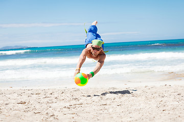 Image showing attractive young man playing volleyball on the beach