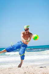 Image showing attractive young man playing volleyball on the beach