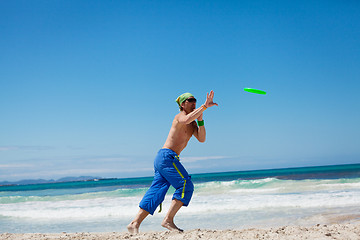 Image showing attractive man playing frisby on beach in summer