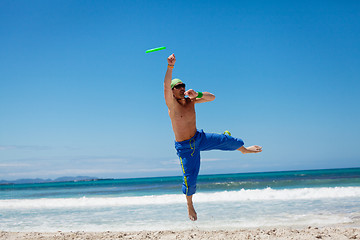 Image showing attractive man playing frisby on beach in summer