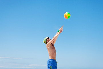 Image showing attractive young man playing volleyball on the beach