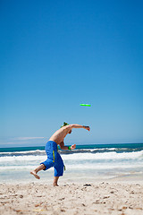 Image showing attractive man playing frisby on beach in summer