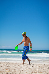 Image showing attractive man playing frisby on beach in summer