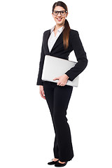 Image showing Young woman in formals posing with a laptop