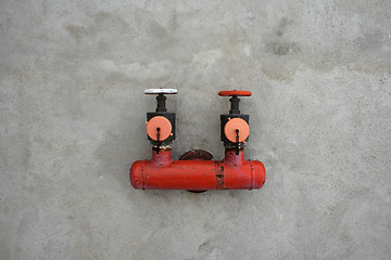 Image showing Red iron valve on a cement wall