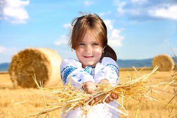 Image showing small rural girl on harvest field with straw bales