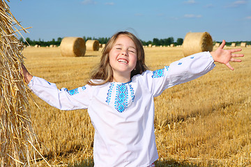 Image showing small rural girl on harvest field with straw bales