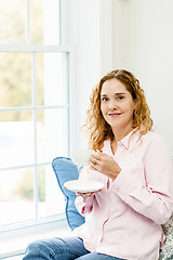 Image showing Woman relaxing by the window with coffee