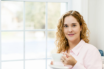 Image showing Woman relaxing by the window with beverage