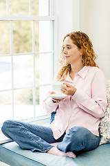 Image showing Woman relaxing by the window with coffee