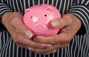 Image showing Elderly hand holding piggy bank