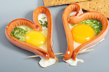 Image showing Two sausages in a heart-shaped fried eggs.