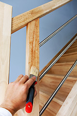 Image showing Hand applying oil on wooden stairs