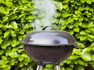 Image showing Old black barbecue being used