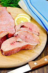 Image showing Fillet of sea bass with a knife on a round board