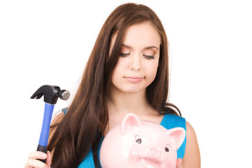 Image showing teenage girl with piggy bank and hammer