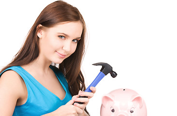 Image showing teenage girl with piggy bank and hammer