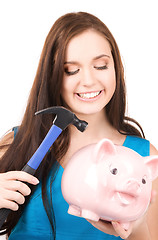 Image showing teenage girl with piggy bank and hammer