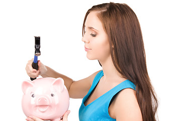 Image showing teenage girl with piggy bank and hammer