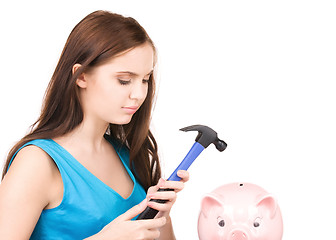 Image showing teenage girl with piggy bank and hammer