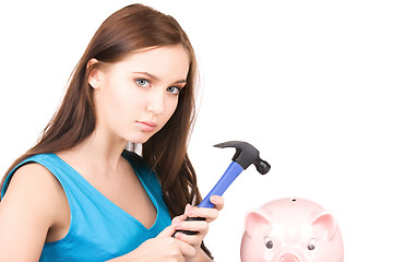 Image showing teenage girl with piggy bank and hammer