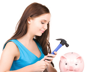 Image showing teenage girl with piggy bank and hammer