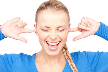 Image showing smiling woman with fingers in ears