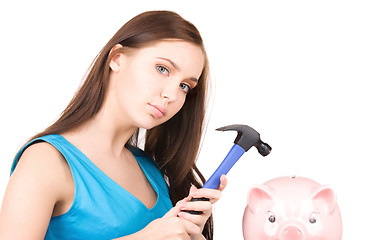 Image showing teenage girl with piggy bank and hammer