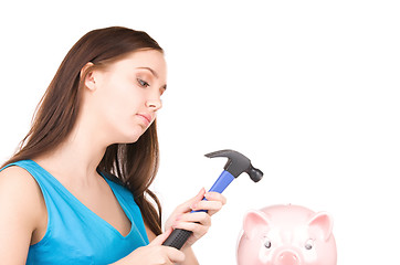 Image showing teenage girl with piggy bank and hammer