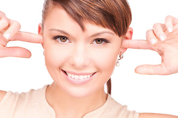 Image showing smiling woman with fingers in ears