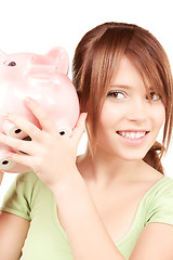 Image showing lovely teenage girl with piggy bank