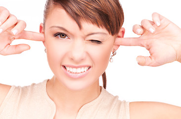 Image showing smiling woman with fingers in ears