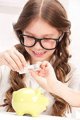 Image showing little girl with piggy bank and money