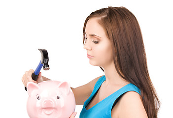 Image showing teenage girl with piggy bank and hammer