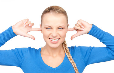 Image showing smiling woman with fingers in ears