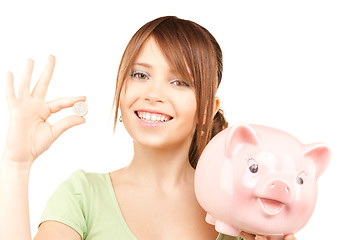 Image showing lovely teenage girl with piggy bank and coin